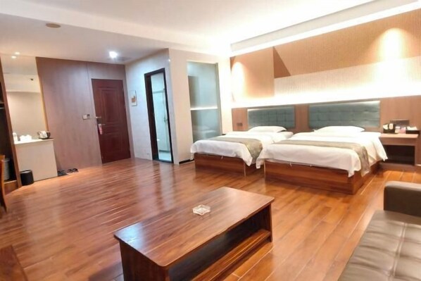 A hotel room with a wooden floor, a bed with two pillows, a bedside table, and a small TV. - Dunhuang Hotel (Dongguan)