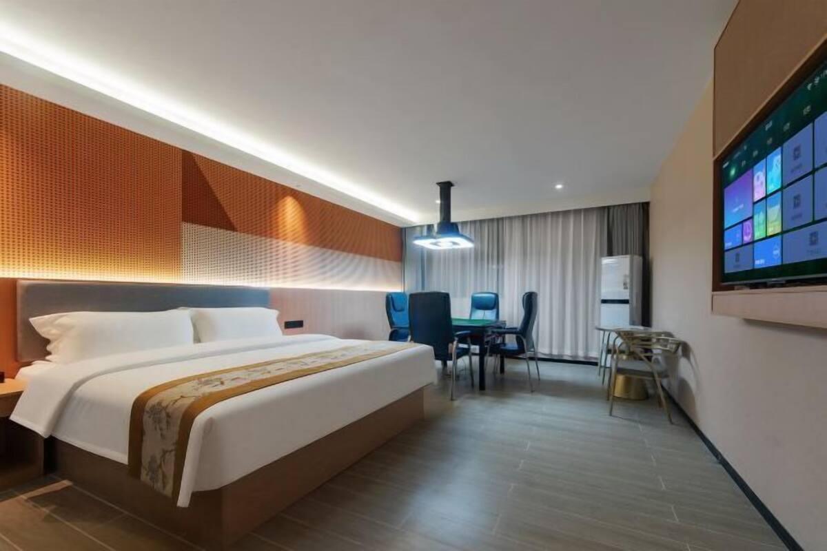 Una habitación de hotel moderna con una cama grande, un escritorio, una silla y una pantalla grande en la pared.