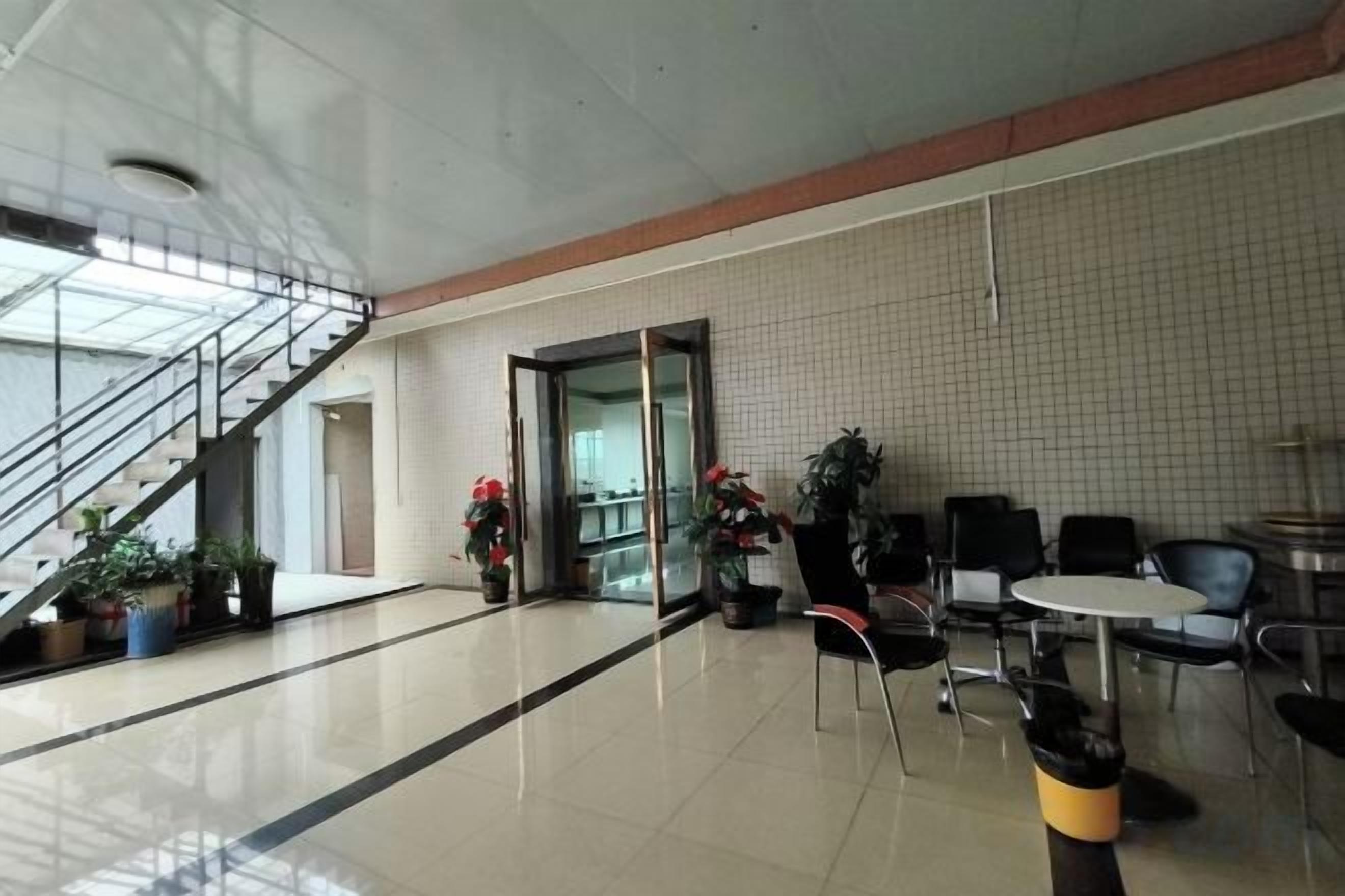 Un amplio espacio interior con escalera, asientos y plantas en macetas.