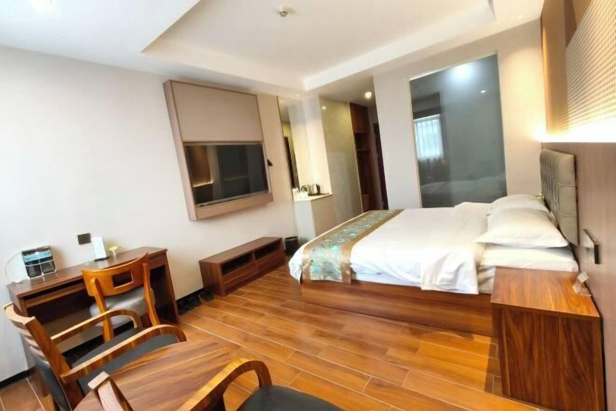 Una habitación de hotel con cama, escritorio, silla y un espejo grande.