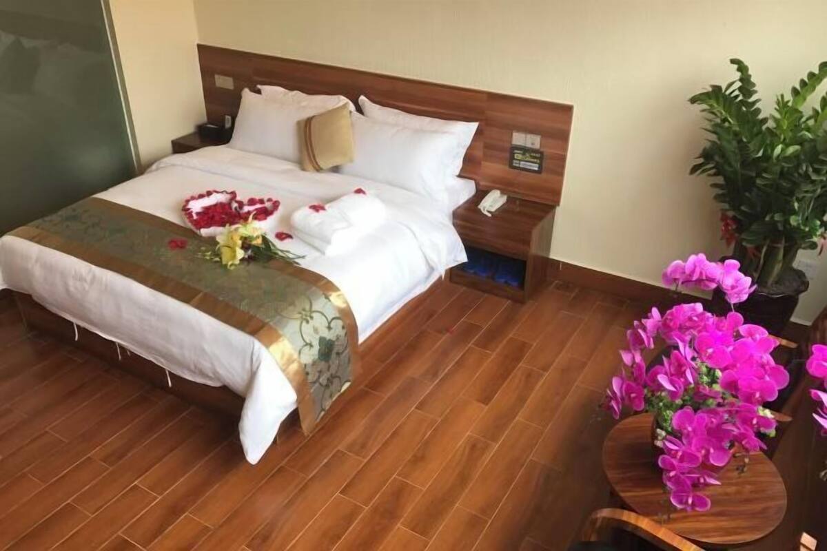 Una cama bien hecha con un arreglo floral y un cabecero de madera.