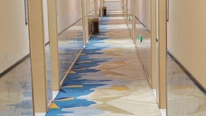 A corridor with patterned flooring and glass partitions.