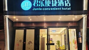 The entrance of Junle convenient hotel with a glass door and a sign above it.