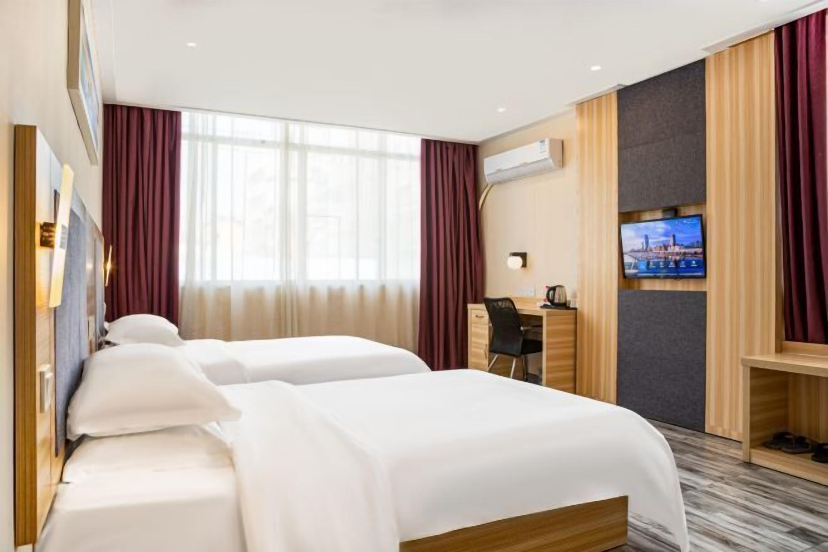 A hotel room with two beds, a desk, a TV, and a shoe rack.