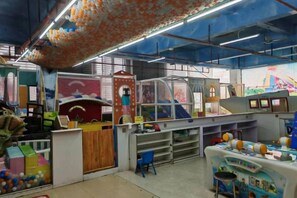 Una sala de juegos con diversas estructuras y juguetes, incluyendo un tobogán y una zona de escalada.