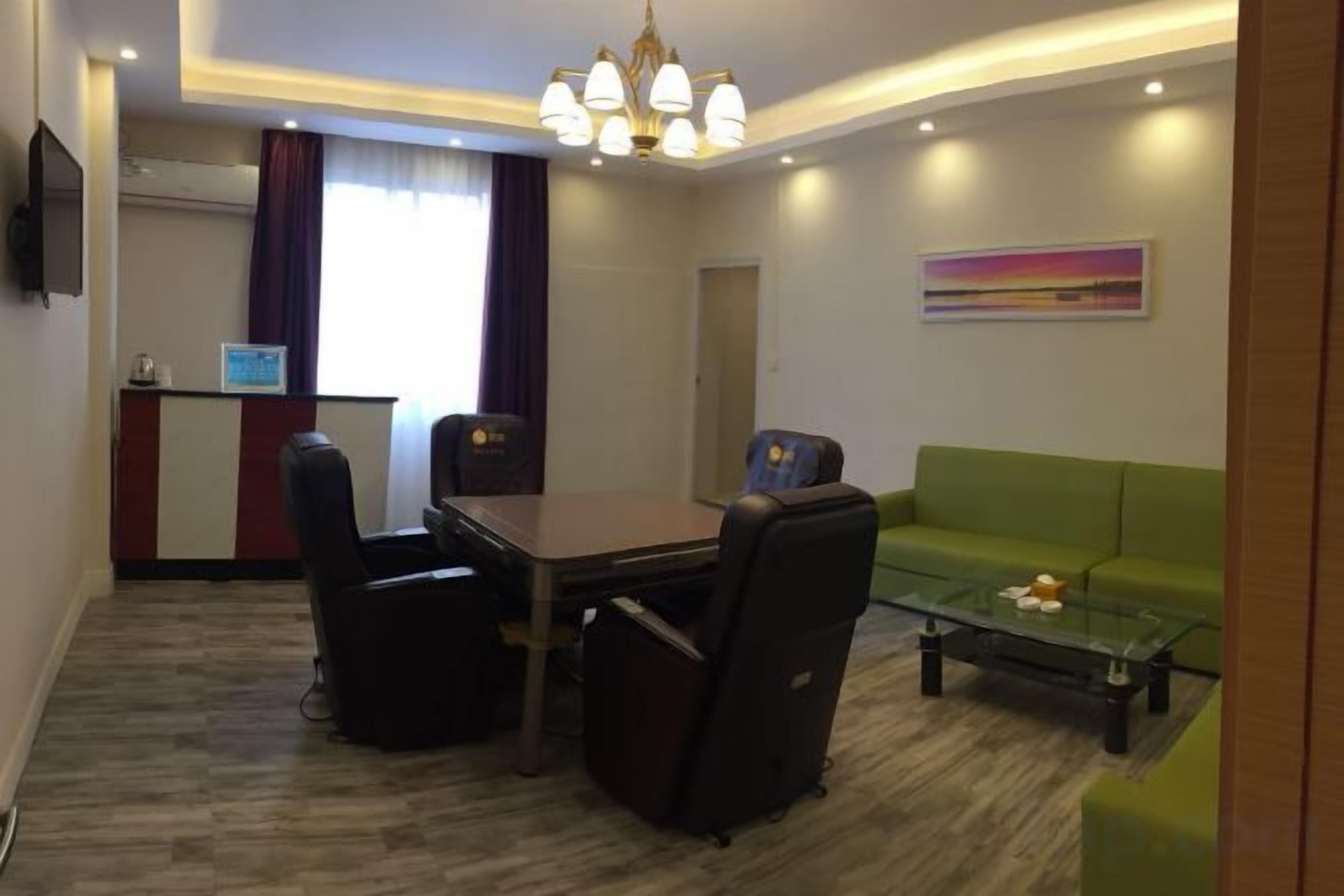 Habitación de hotel con una mesa de comedor, sillas, un sofá, una mesa de centro, un televisor y un cuadro en la pared.