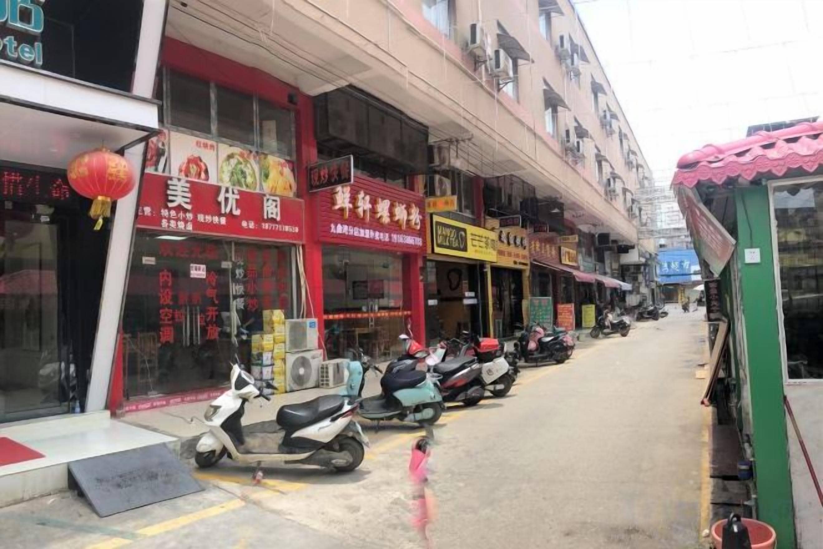 A street with shops and parked scooters.