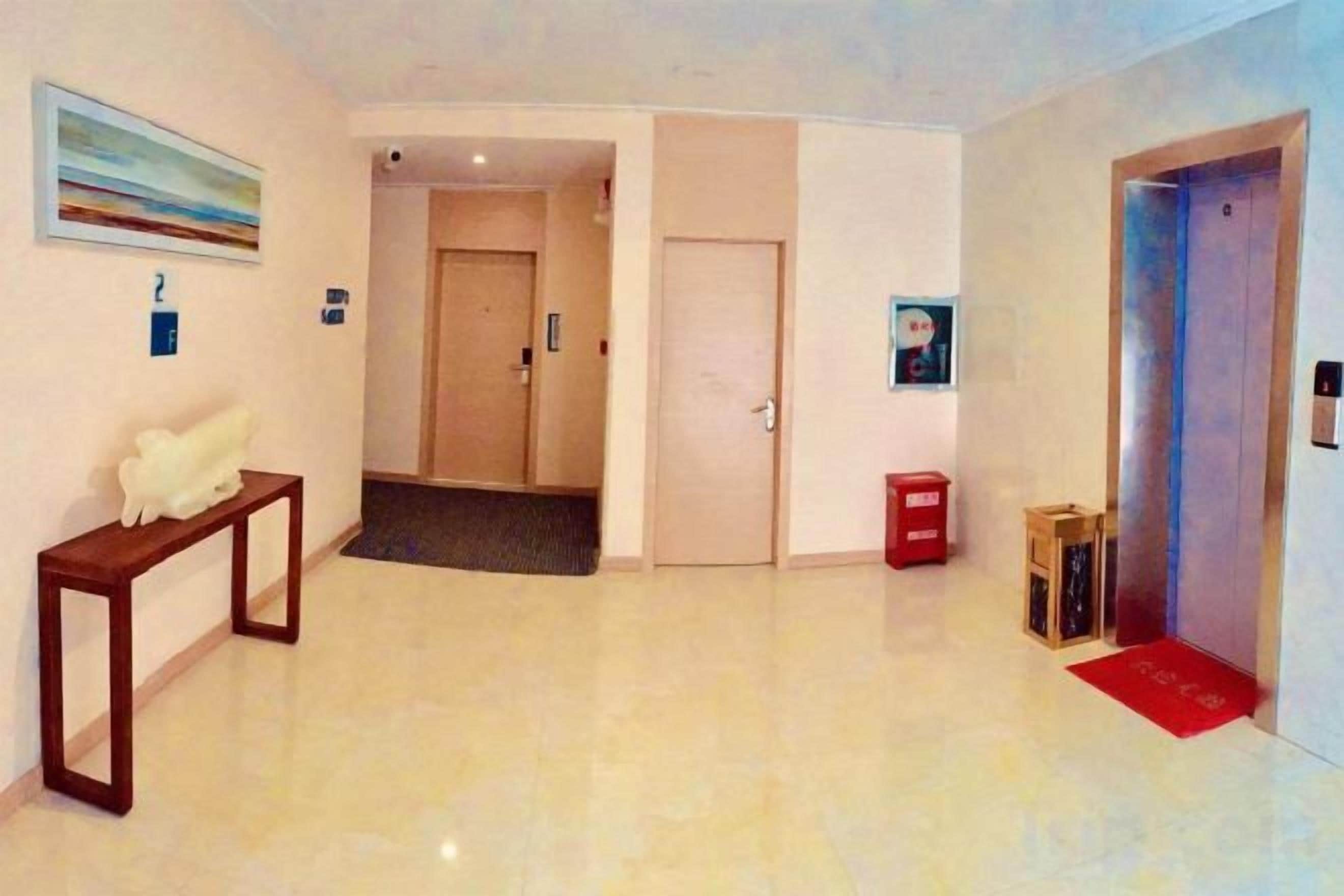 Un vestíbulo de hotel con un mostrador de recepción, una puerta que da a una habitación y un ascensor.