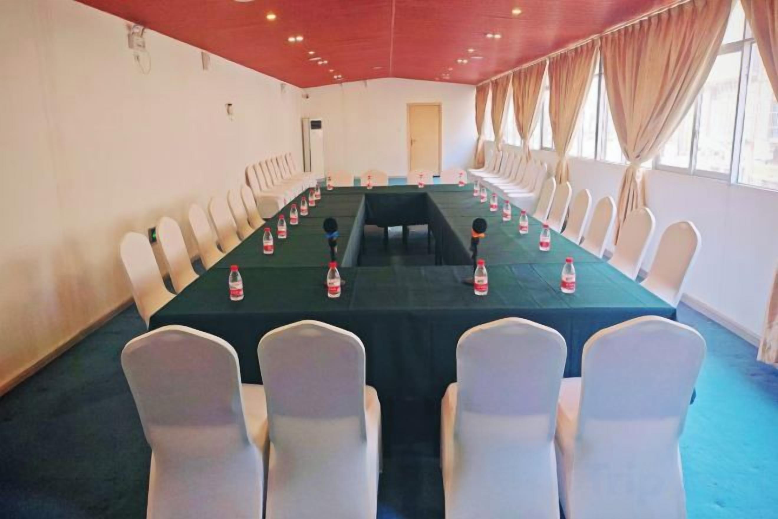 A conference room with a long table, white chairs, and a red ceiling.