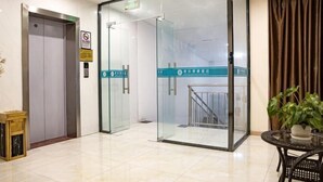 A modern elevator with glass doors, a no-smoking sign, and a sign indicating a hotel.
