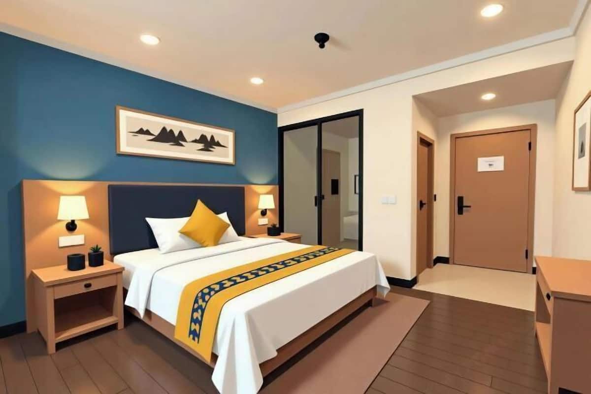 A hotel room with a bed, nightstands, a desk, and a door.