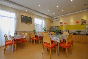 Área de refeições com mesa e cadeiras, cozinha com bancada e ar-condicionado fixado na parede.