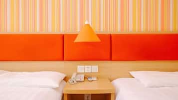 A hotel room with two beds, a wooden nightstand with a lamp, and a striped wall.