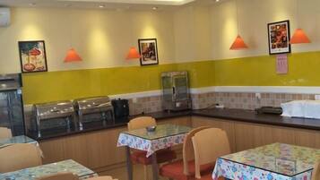 A restaurant interior with tables, chairs, and a counter with food display.