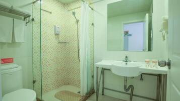 A bathroom with a toilet, a glass shower enclosure, a sink, and a mirror.