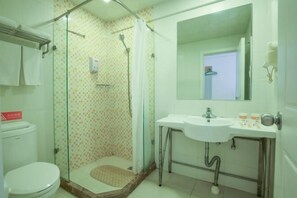 A bathroom with a toilet, a glass shower enclosure, a sink, and a mirror. - Pebble Motel (Kunming Dounan Flower City Longcheng Street) (Kunming)