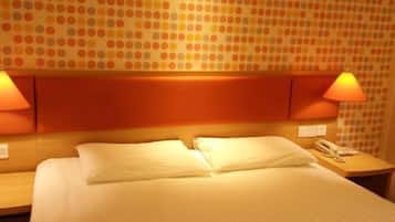A hotel room with a bed, two bedside lamps, a telephone, and a wall with a polka dot pattern.