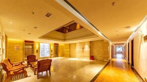 Un hall d’hôtel avec un long couloir, des meubles en bois et un mur en pierre.