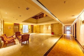 Een hotel lobby met een lange gang, houten meubels en een stenen muur.