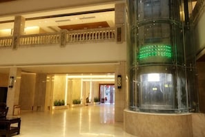A spacious lobby with a marble floor, a glass elevator, and a second-floor balcony. - Guanhailou Holiday Hotel (Maoming)