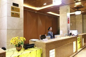 Un mostrador de recepción con una computadora, un florero y un cartel en la pared.