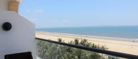 A balcony with a view of a beach and palm trees.