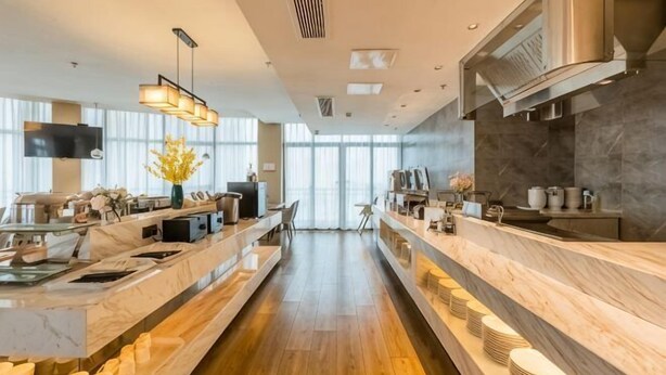 A modern kitchen with marble countertops, a central island, and a long counter. - Gya Hotel (Nantong Nanshanhu Shuijie) (Nantong)