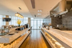 A modern kitchen with marble countertops, a central island, and a long counter.