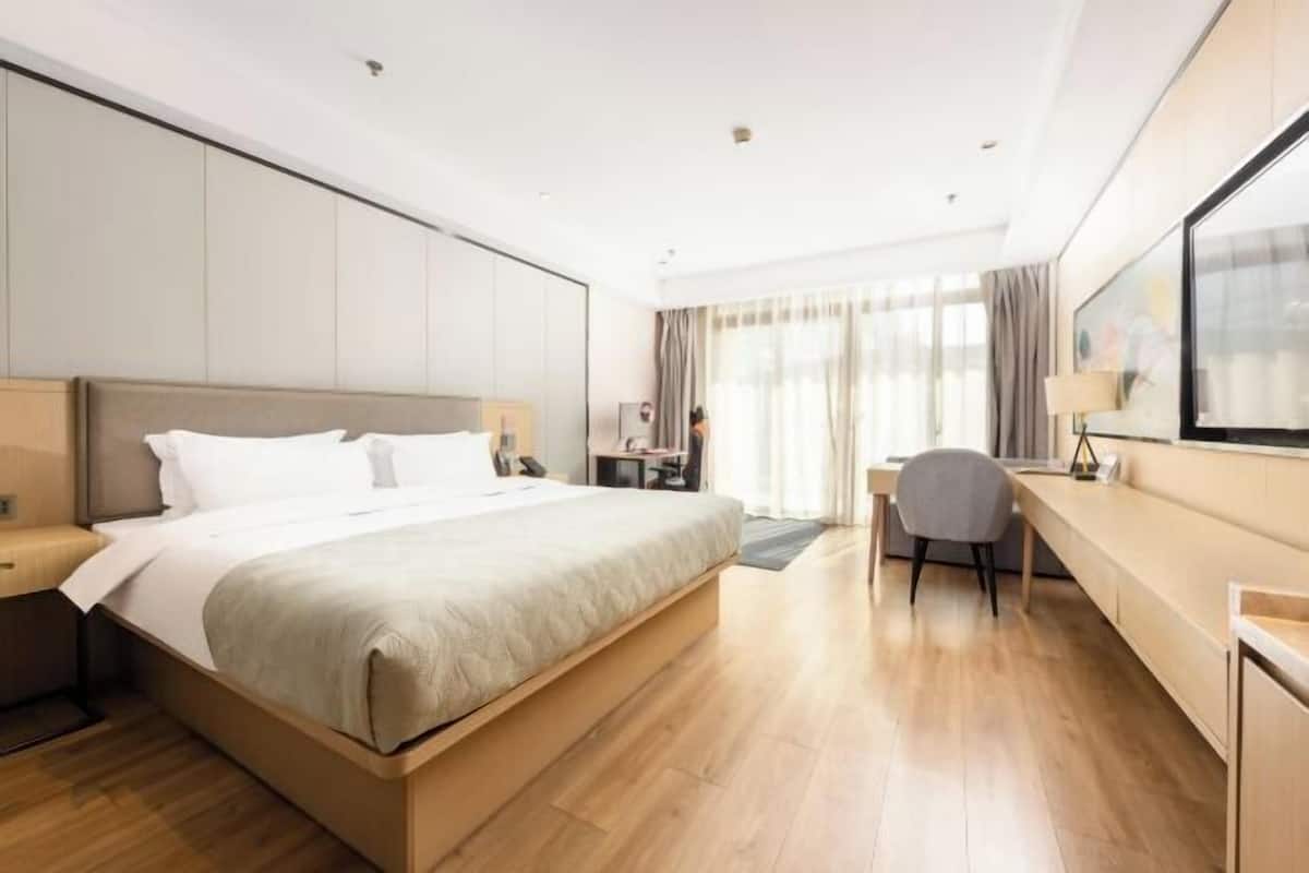 Ein modernes Hotelzimmer mit einem großen Bett, einem Schreibtisch und einem Fernseher.