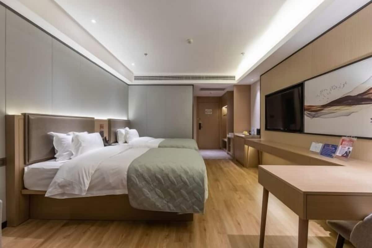 Ein Hotelzimmer mit einem großen Bett, einem Schreibtisch, einem Fernseher und einem Bild an der Wand.