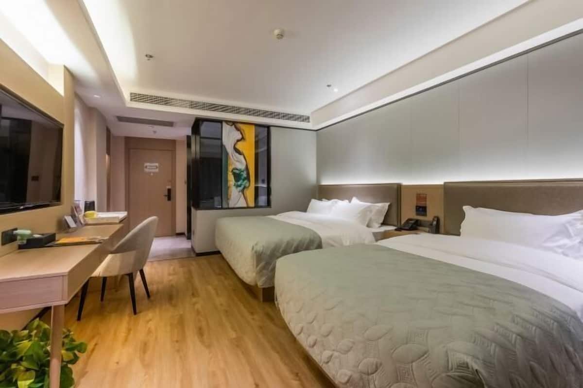 Ein Hotelzimmer mit zwei Betten, einem Schreibtisch und einem Stuhl.