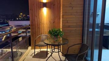 Un balcón con mesa y sillas, una planta en maceta y vistas a la ciudad.
