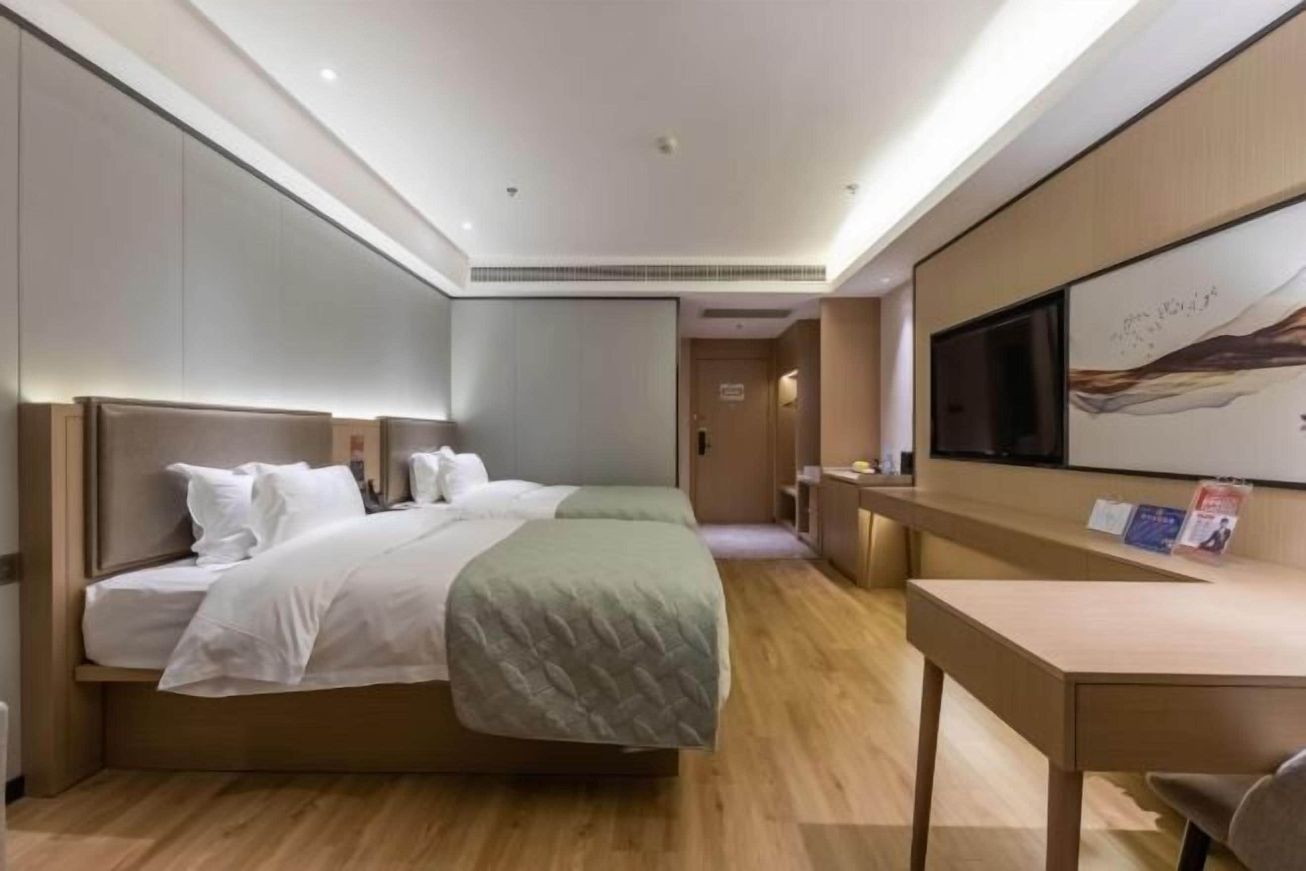 Una habitación de hotel moderna con una cama grande, un escritorio y un televisor.