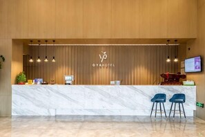 Un comptoir d’accueil avec un panneau en bois en arrière-plan, un comptoir en marbre et deux tabourets de bar.