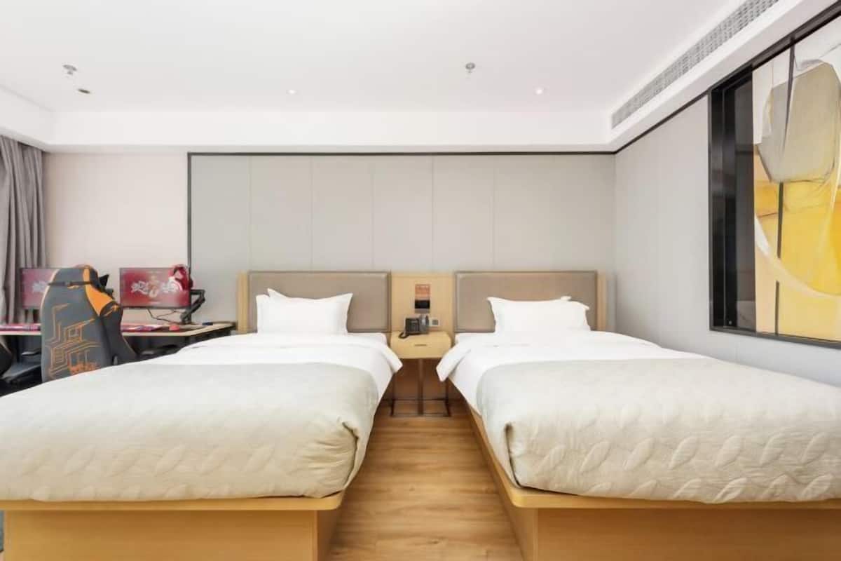 Ein Hotelzimmer mit zwei Betten, einem Schreibtisch, einem Stuhl und einem großen Fenster.