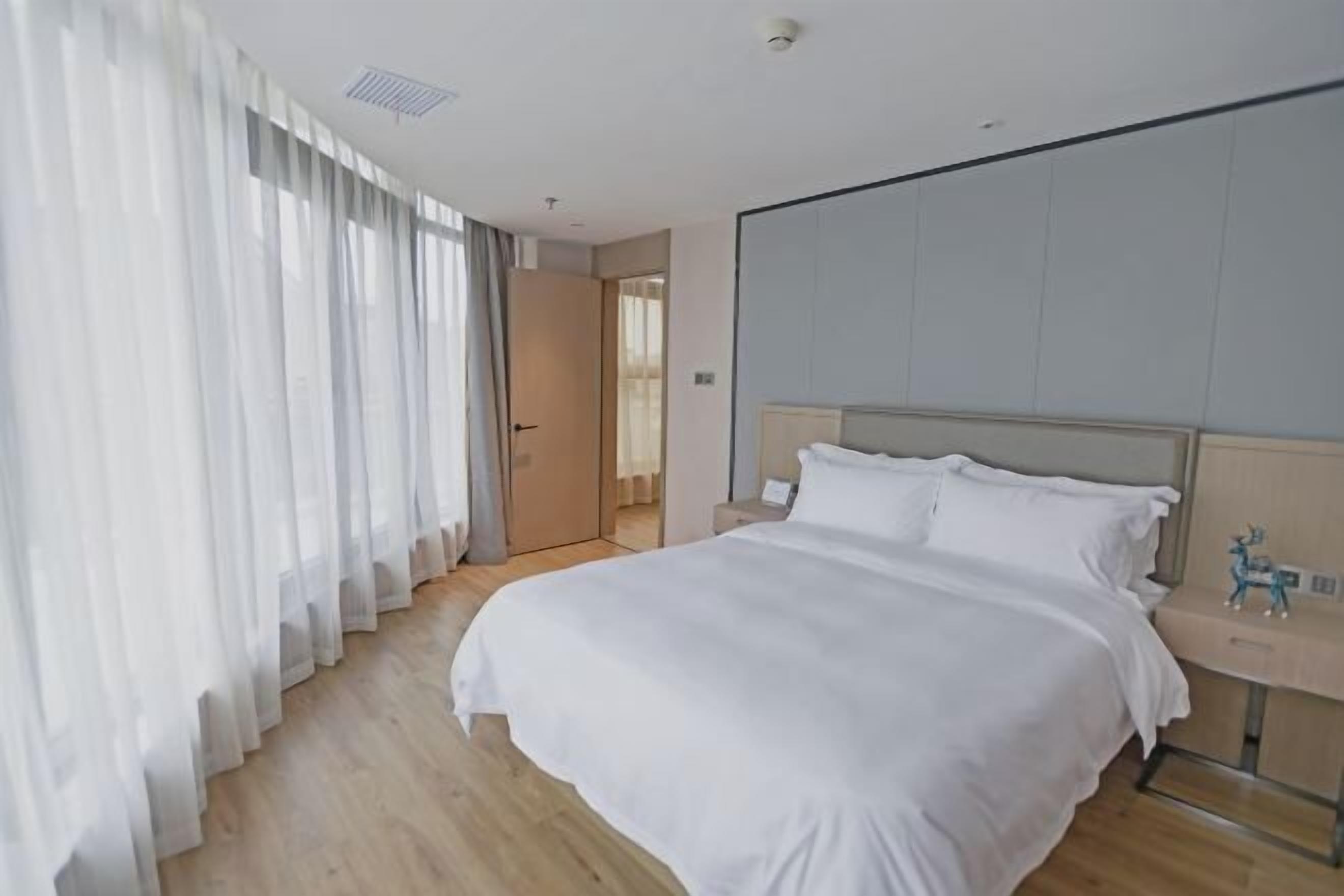 Una habitación de hotel con una cama grande, una mesita de noche y una puerta que da a otra habitación.