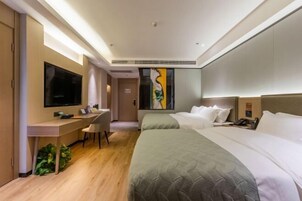 Habitación de hotel con escritorio, dos camas, televisión y un cuadro en la pared.