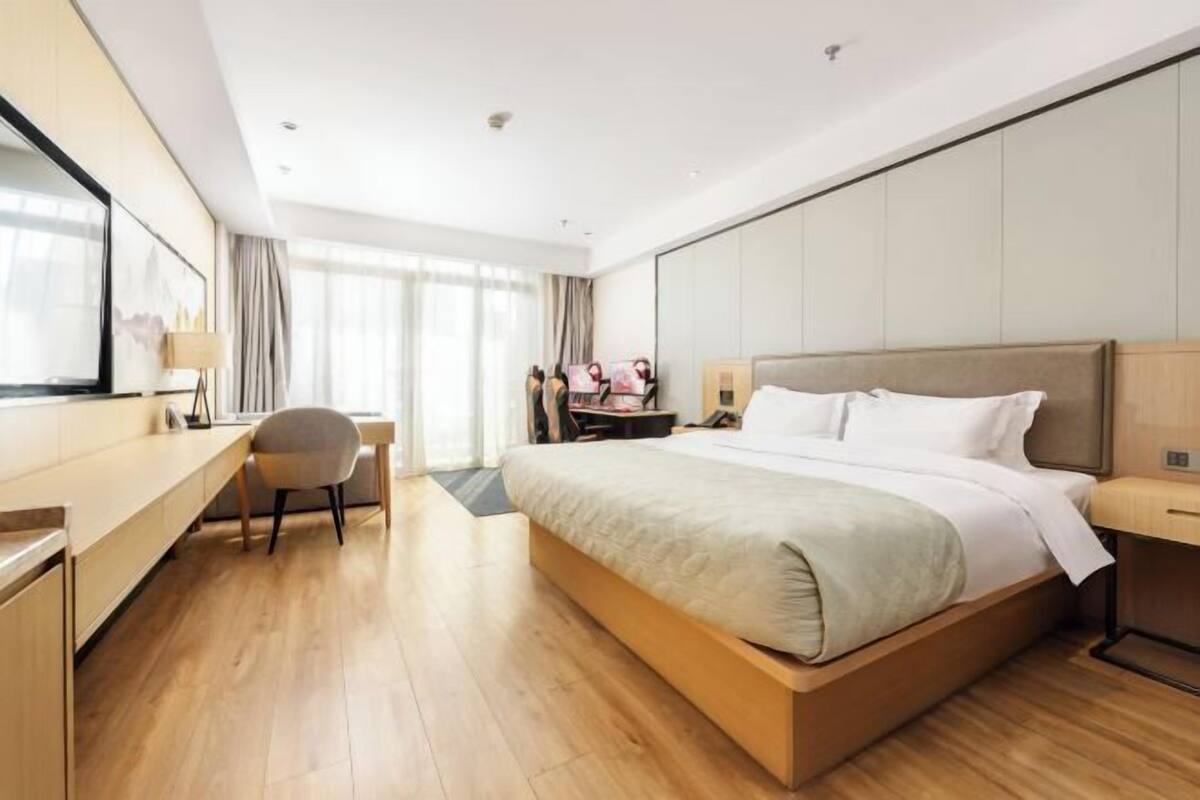 Ein modernes Hotelzimmer mit einem großen Bett, einem Schreibtisch und einem Sessel.