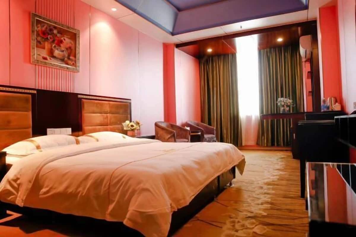 A hotel room with a large bed, a desk, a chair, and a view of the outdoors.
