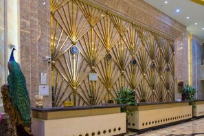 A reception area with a decorative wall featuring geometric patterns and a peacock statue. - Duxiu Hotel (Tacheng City)