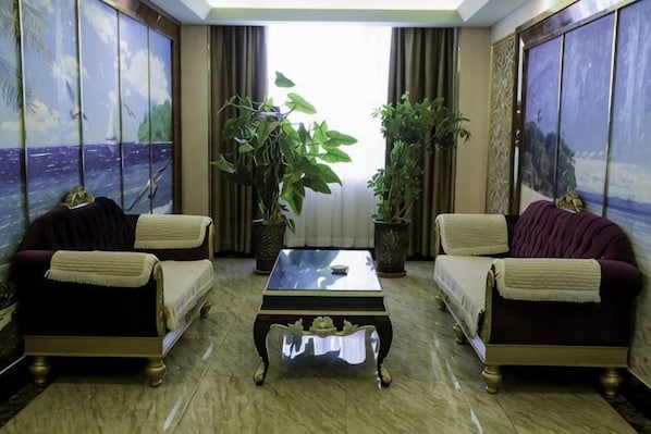 Una habitación con dos sofás orientados hacia un ventanal amplio, una mesita de centro y dos plantas en macetas.