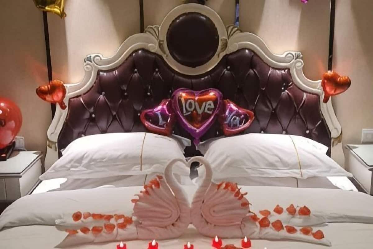 A bed with a heart-shaped pillow arrangement and a swan design made of pillows.