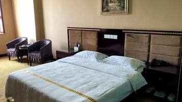 Una habitación de hotel con cama, una silla, una mesita de noche y un cuadro en la pared.