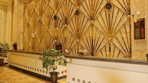 Un espace d’accueil agrémenté d’un mur décoratif, d’un comptoir de réception et de plantes en pot.