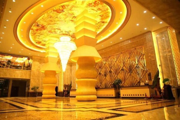 Un hall d’entrée agrémenté d’un grand lustre, d’un comptoir de réception et d’un mur décoratif.