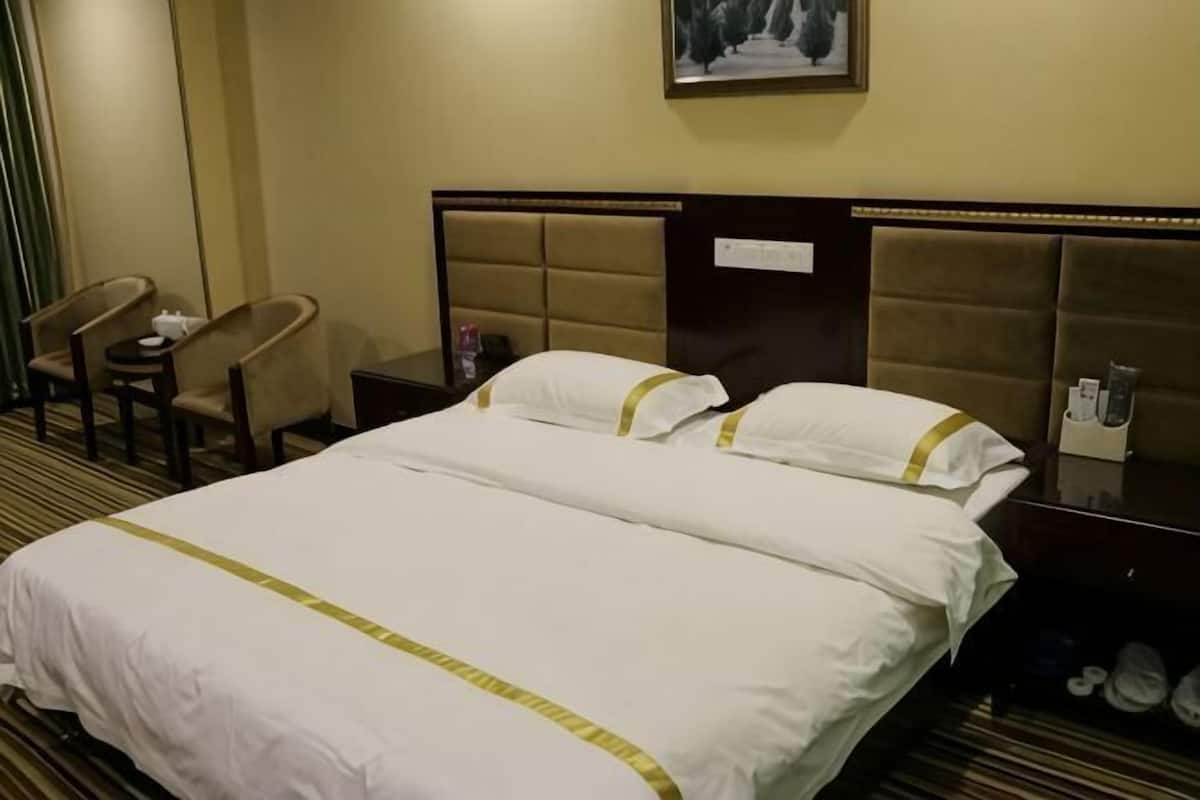A hotel room with a large bed, a nightstand, a chair, and a small table.