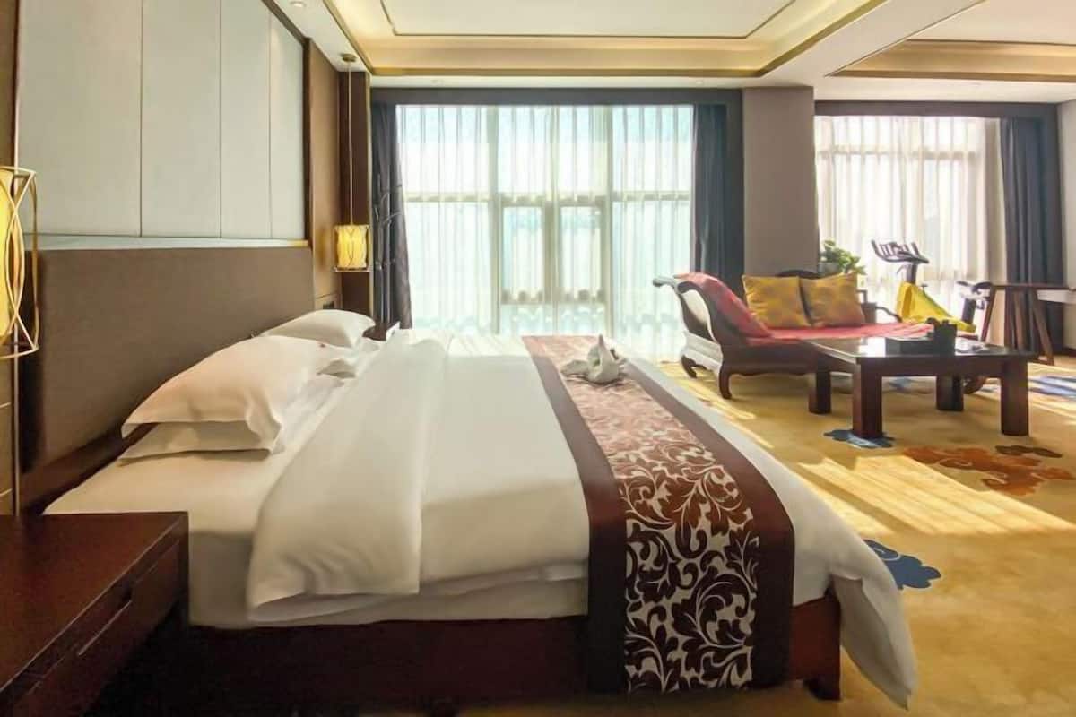 A hotel room with a bed, a sofa, a table, and a chair.