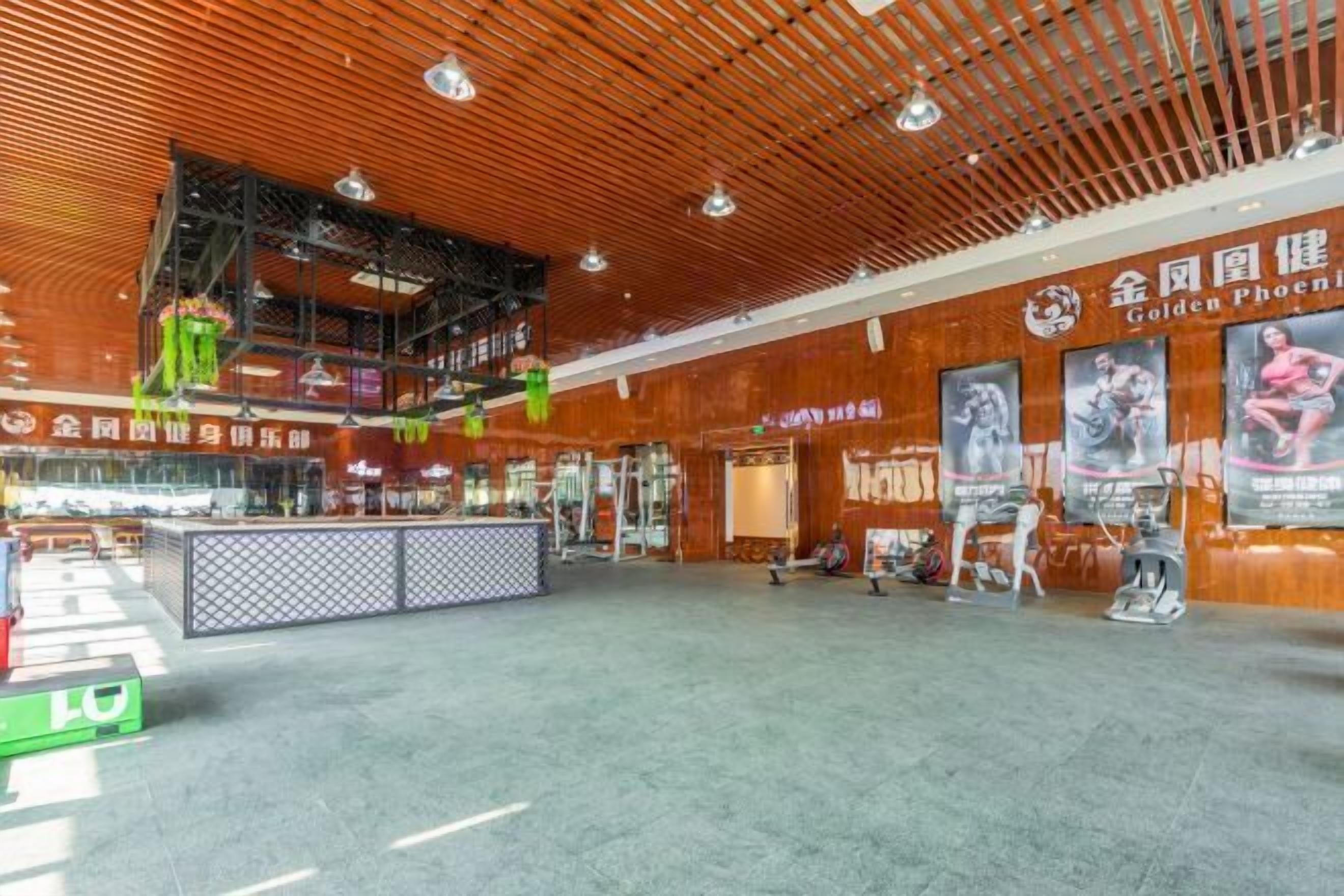 Un gimnasio amplio con equipo de ejercicio, un mostrador de recepción y carteles motivacionales en las paredes.