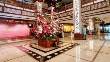 A lobby with a floral centerpiece, a reception desk, and a traditional architectural design.