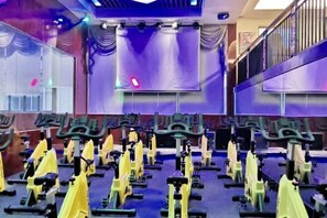 Ein Fitnessraum mit mehreren Fahrrädern, violetten Wänden und einer Spiegeldecke.